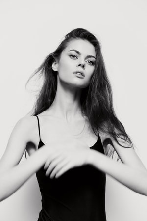 Elegant young woman with long hair in black top, posing with natural beauty and confidence. Black and white portrait emphasizing grace and poise.の写真素材