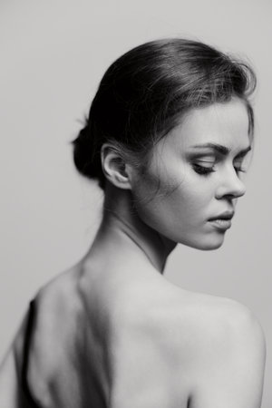 Elegant portrait of a contemplative woman with a graceful pose, showcasing natural beauty and confidence. Soft lighting enhances her features in a monochromatic setting.の写真素材