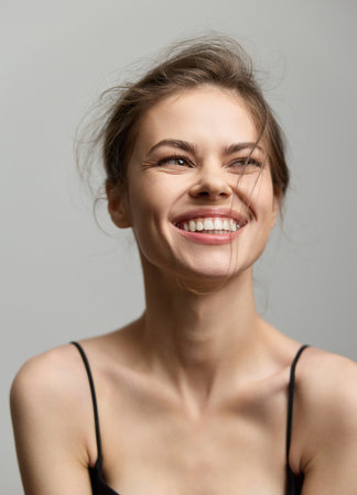 Joyful young woman with a radiant smile, showcasing natural beauty and carefree attitude. Simple background emphasizes her joyful expression and casual style.の写真素材