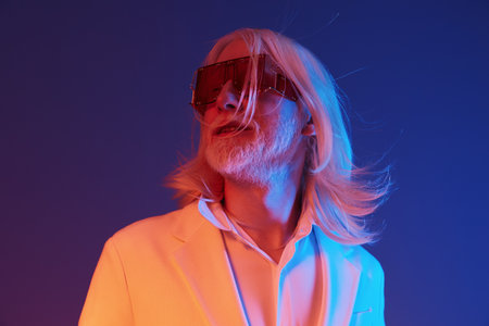 Stylish man with long white hair and oversized sunglasses against a vibrant blue and pink...