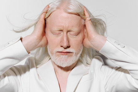 Emotion, stress relief, human expression A serene elderly person with white hair and a beard, wearing a white suit, against a plain white backgroundの写真素材