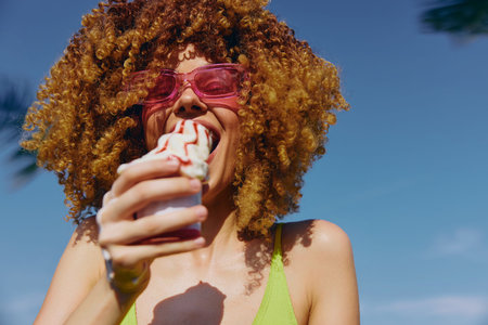 Joyful woman enjoying ice cream on a sunny day in a vibrant green outfit Bright blue sky and palm trees set a cheerful summer sceneの写真素材