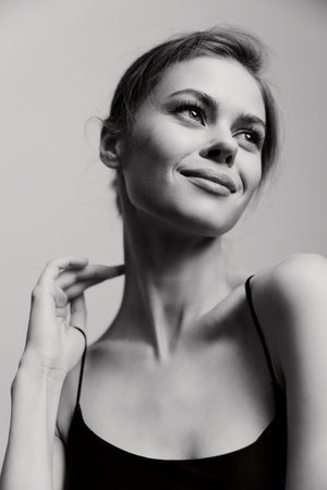 Elegant young woman with a serene expression, showcasing natural beauty and confidence. Soft light highlighting facial features against a simple background.の写真素材