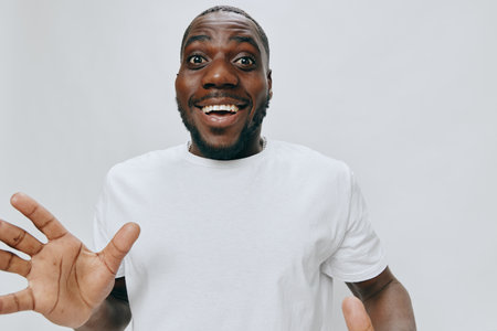 Happy young man expressing excitement and joy in a white t shirt with hands raised, cheerful emotions captured against a clean white background Great for positivity conceptsの写真素材