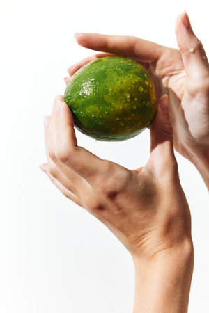 Person holding a green fruit in hand on white background