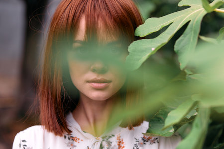 Vibrant redhaired woman standing in lush green garden surrounded by plants and trees