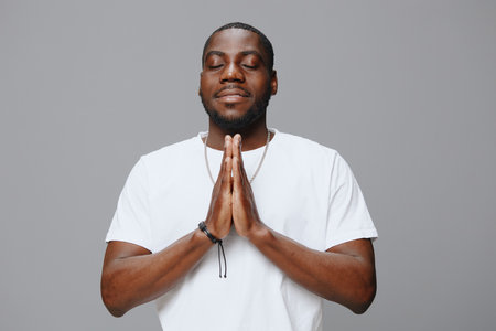 Prayerful man, gratitude expression, peaceful demeanor, African descent, casual white T shirt,...