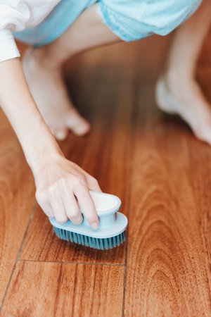 Person cleaning hardwood floor with brush and white towel in frontの写真素材