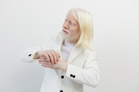 elderly man with long white hair wearing a white suit, pondering thoughtfully against a plain white background, conveying wisdom and serenity in a minimalist settingの写真素材
