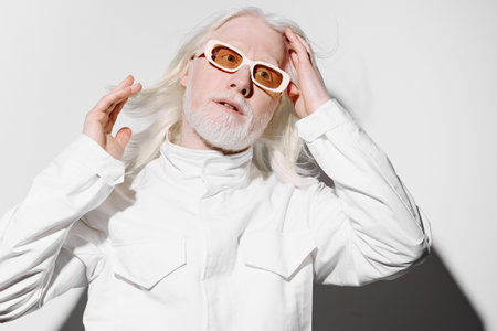 A stylish individual with long white hair and light skin, wearing trendy sunglasses and a white jacket, posed against a minimalist white background, portraying modern fashionの写真素材