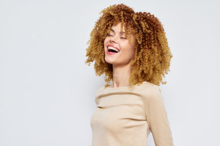 Smiling woman with curly hair enjoying life, light background, joyful expression, casual fashion,...