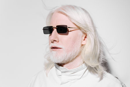 Man with long white hair and sunglasses against a minimalistic white background, exuding a modern and stylish vibe in a fashion forward conceptの写真素材