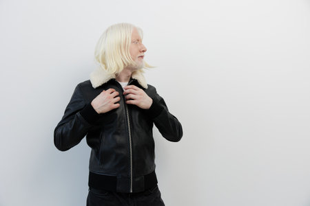 Young person wearing a stylish black leather jacket with a faux fur collar, standing against a clean white background, exuding confidence and a modern vibeの写真素材