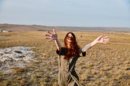 Freedom in the field a woman standing with hands up in travel adventure nature beauty conceptの写真素材