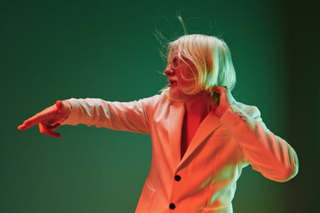 Stylish blonde person in a modern suit against a gradient green background, portraying confidence...