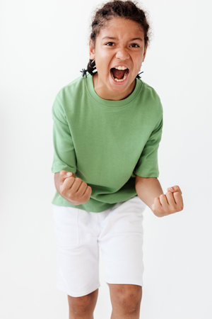 Confident young boy in stylish outfit showing determination with clenched fistsの写真素材