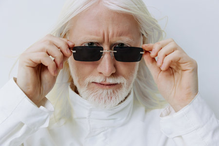 portrait of an elderly man with long white hair wearing sunglasses, set against a minimalistic light...