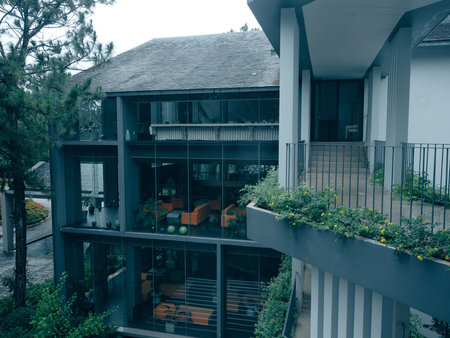 Modern architectural design featuring a sleek building with large glass windows and greenery, showcasing a contemporary lifestyle aestheticの写真素材