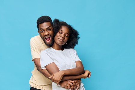 Happy young couple embracing each other against a blue background, showcasing love and joy, perfect for seasonal themes and relationship conceptsの写真素材