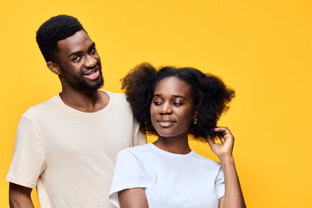 Happy couple standing against a bright yellow background, showcasing their natural hair and joyful expressions, depicting love and connectionの写真素材
