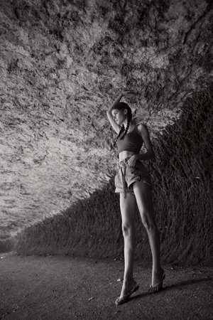 Exploring the mysteries of the underground cave with a woman standing alone in black and whiteの写真素材