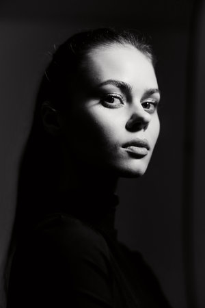 Portrait of a confident young woman with long hair, standing against a dark background, showcasing...