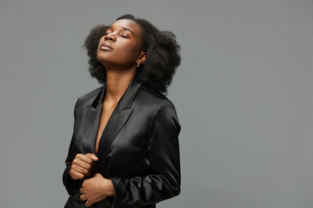 Confident young woman with natural hair in a black blazer, exuding calmness and self assuredness...