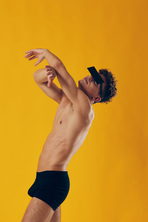 Confident male model posing with unique sunglasses against a vibrant yellow background, showcasing modern fashion and self-expression.の写真素材