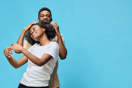 Happy young African couple enjoying quality time together against a vibrant blue backdrop, radiating love and joy in casual clothingの写真素材