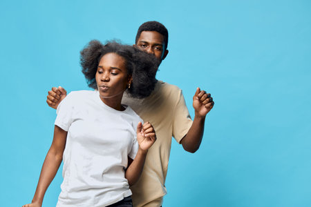 Two young friends dancing together against a bright blue background, showcasing joy and connection...