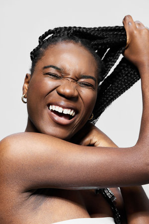 Smiling African woman with braided hair enjoying self care, showcasing beauty and positivity in a...