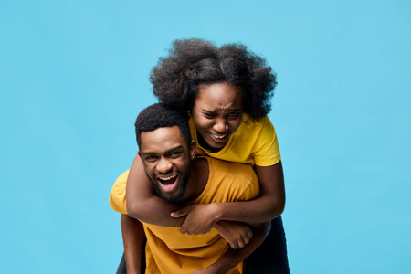 Happy couple laughing together against a bright blue background, showcasing joy and love, perfect for seasonal celebrations or romantic themesの写真素材