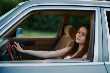 A young woman reflecting while sitting in a classic car, showcasing a thoughtful expression and vintage interior, perfect for automotive and lifestyle themes.の写真素材