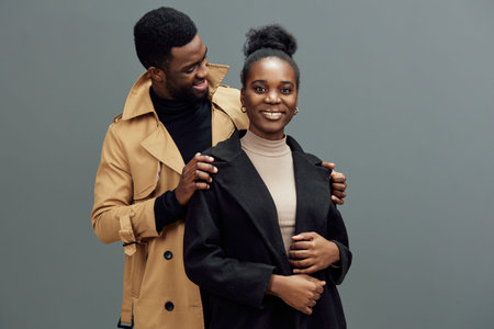 Happy couple posing together in stylish winter outfits the woman wears a black coat and the man a...