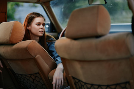 Young woman in casual attire sitting in car relaxing, showcasing thoughtful expression and natural...