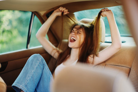Young woman expressing frustration while pulling her hair in a car, surrounded by a lush green...