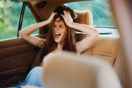 A young woman expressing frustration and joy in a car, showcasing vibrant emotions against a bright green background, perfect for relatable lifestyle concepts.の写真素材
