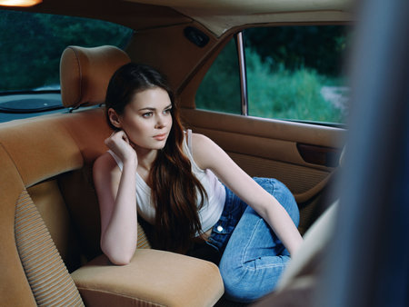 Young woman in casual attire relaxing in a car, expressing thoughtful emotions with a natural...