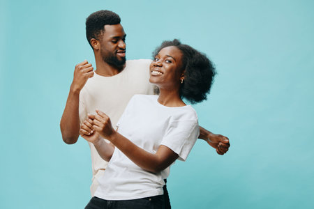 Happy young couple dancing together, showcasing joy and connection against a light blue background,...