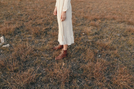 Woman in white dress standing in brown field during travel adventure beauty in nature conceptの写真素材