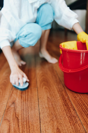 Woman cleaning wooden floor with bucket and mop, red bucket and red mop in the backgroundの写真素材