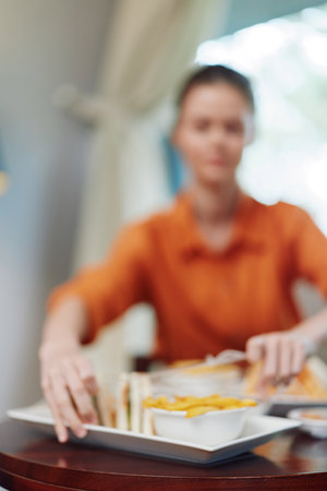 Woman enjoying healthy meal in cozy caf setting, featuring vibrant fruits and vegetables on a plate,...