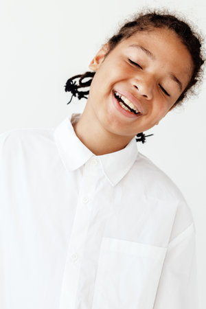 Happy young boy in white shirt smiling brightly against white backgroundの写真素材