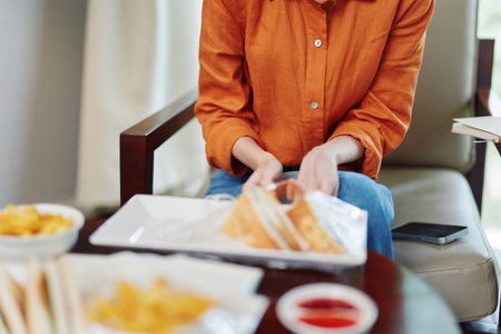 A woman in an orange shirt enjoys a healthy meal, showcasing vibrant colors and a cozy setting, emphasizing nutritious eating habits and lifestyle choicesの写真素材