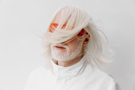 elderly man with long white hair and stylish orange sunglasses, wearing a white outfit on a minimalistic white background, creating a modern and artistic vibeの写真素材