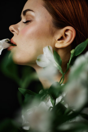 Portrait of a serene woman with closed eyes, elegantly holding a flower, surrounded by lush greenery, showcasing beauty and natureの写真素材