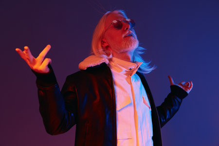 Stylish elderly man with long silver hair and sunglasses striking a confident pose, wearing a black...