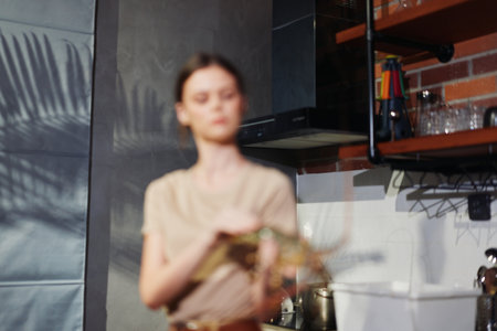 Woman cooking in kitchen with pot on stove and knife in hand