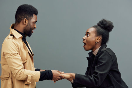 Excited couple sharing joyful moment, surprised expressions, modern fashion, emotional connection, gray background, perfect for relationship conceptsの写真素材