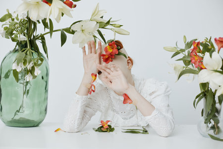 A serene composition of a model surrounded by vibrant flowers, conveying emotions of tranquility and self acceptance in a minimalist settingの写真素材